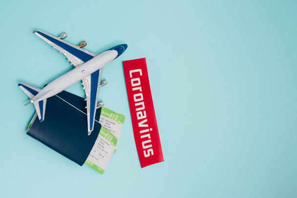 Κάτοψη του παιχνιδιού κοντά σε κάρτα με γράμματα coronavirus και διαβατήρια με αεροπορικά εισιτήρια σε μπλε - Φωτογραφία, εικόνα