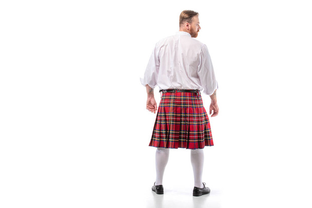 back view of Scottish redhead man in red kilt on white background - Foto, afbeelding