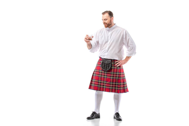 Skót vörös hajú férfi piros skót szoknyában whiskyvel üvegben fehér alapon - Fotó, kép