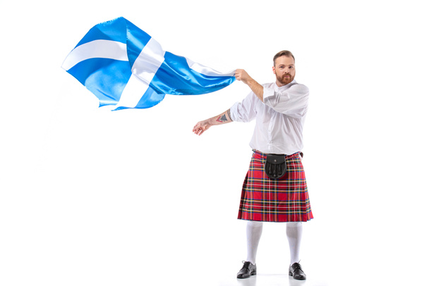 Scottish redhead man in red kilt with flag of Scotland on white background - Foto, immagini