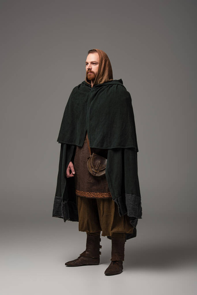 medieval Scottish redhead man in mantel on grey background - Foto, afbeelding