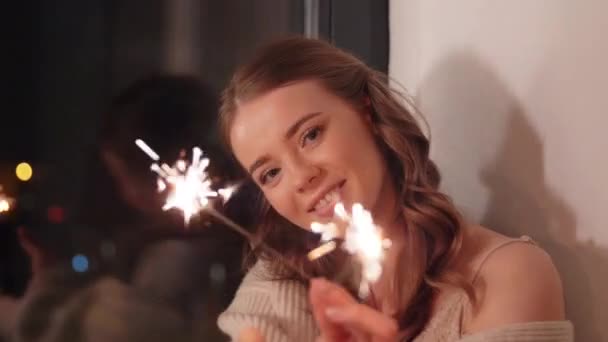 happy young woman with sparklers at home - Záběry, video