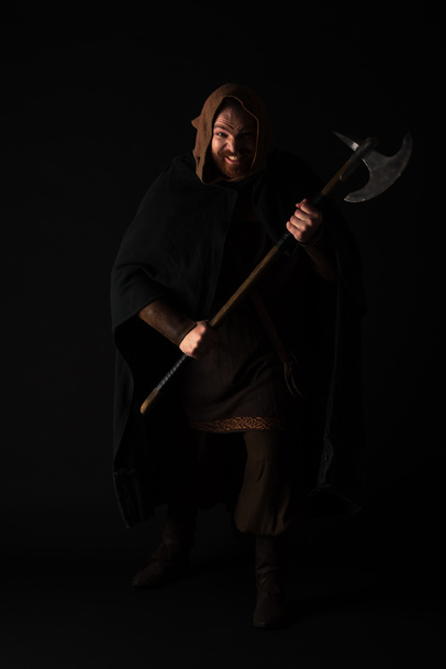 gekke middeleeuwse Schotse krijger met strijdbijl in mantel geïsoleerd op zwart - Foto, afbeelding