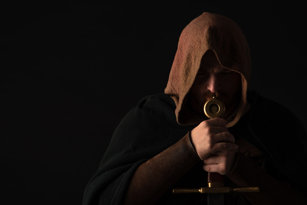 medieval escocés hombre en mantel con espada en oscuro aislado en negro
 - Foto, Imagen