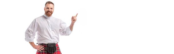 homme barbu rousse écossais souriant en kilt de tartan rouge pointant du doigt isolé sur blanc, en-tête du site
 - Photo, image
