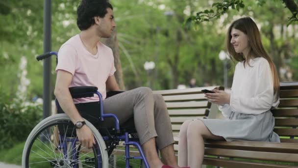 Tekerlekli sandalyedeki genç adam ve parkta buluşan kadın. - Video, Çekim