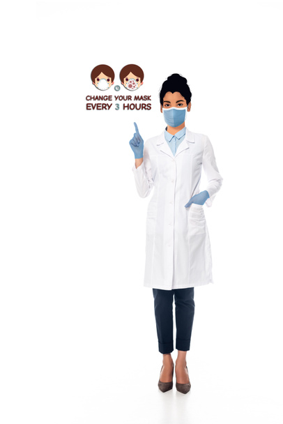 Afrikaans-Amerikaanse arts met geïllustreerd gezicht in medisch masker wijzen met de vinger naar verander je masker om de 3 uur illustratie op wit - Foto, afbeelding