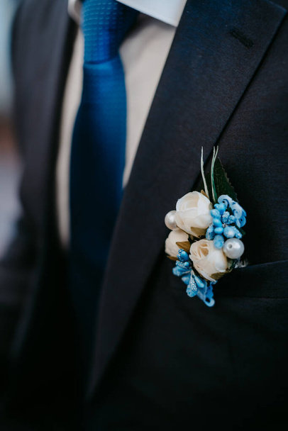 Τεχνητό λουλούδι μπουτονιέρα στο μπλε σακάκι του γαμπρού - Φωτογραφία, εικόνα
