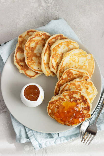American pancakes or fritters with orange jam on ceramic plate. Light grey stone background.  - Φωτογραφία, εικόνα