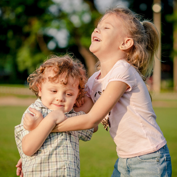 двое счастливых маленьких детей играют в парке в дневное время
 - Фото, изображение