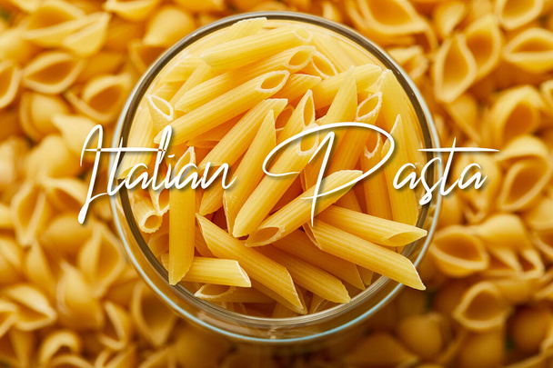 top view of raw penne in jar and around with Italian pasta illustration - 写真・画像