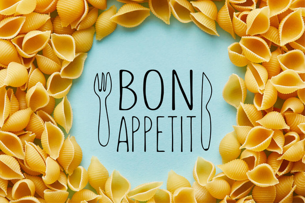 round frame of raw Conchiglie on blue background with bon appetit illustration - Photo, Image