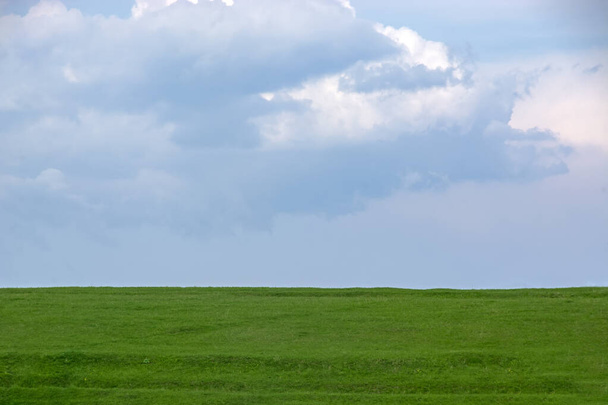 Campo de grama verde em um fundo do céu azul nublado. Fundo natural perfeito para texto e design
 - Foto, Imagem