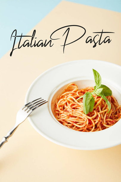Mavi ve sarı arka planda çatalın yanında domates soslu leziz spagetti İtalyan makarna resimli. - Fotoğraf, Görsel