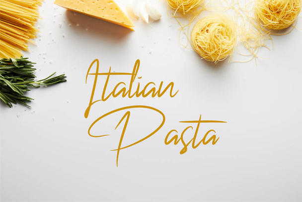Top view of rosemary, garlic, cheese and pasta on white background, italian pasta illustration - Фото, изображение
