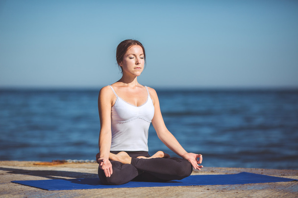Young woman, sea shore, yoga exercises - 写真・画像