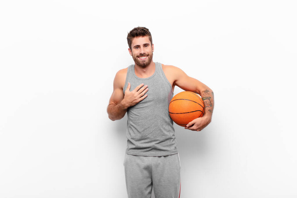 young handsome man looking happy, surprised, proud and excited, pointing to self holding a basketball ball. - 写真・画像