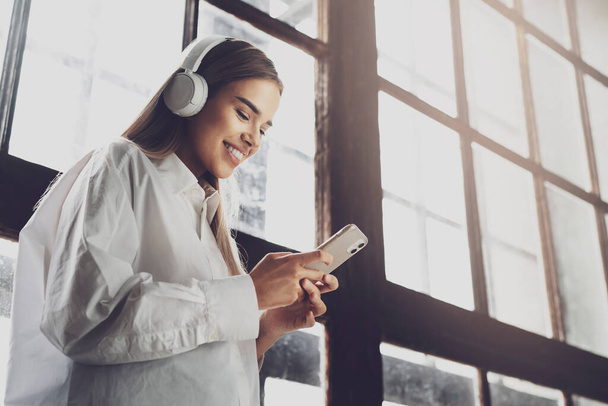 Pretty young girl in wireless headphones listening to music on smartphone. Online apps for mobile devices - Fotoğraf, Görsel