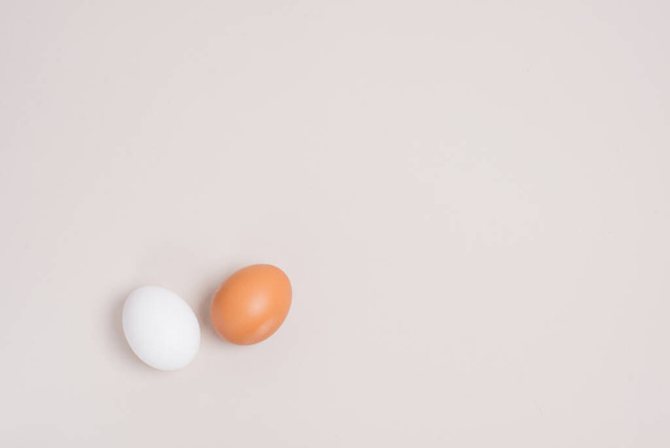 two eggs white and brown on a beige background - 写真・画像