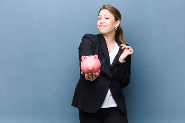 young blonde woman with a piggy bank against grunge wall background - Valokuva, kuva