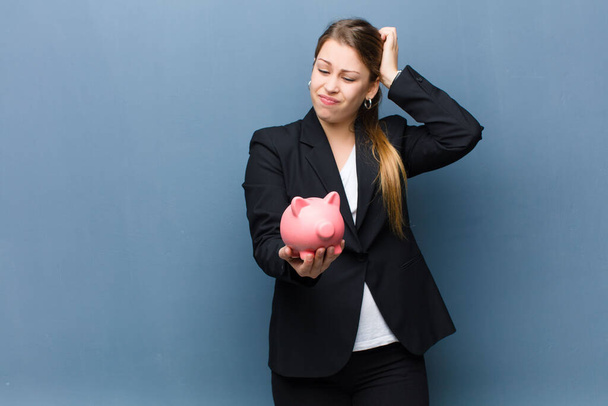 young blonde woman with a piggy bank against grunge wall background - Photo, image
