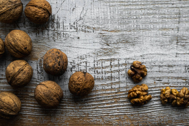 Walnut scattered on the wooden vintage table. Walnuts is a healthy vegetarian protein nutritious food. Walnut on rustic old wood. Copy space. - Photo, image
