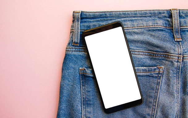 Smartphone de pantalla blanca en bolsillo vaquero. Smartphone lugar para el texto. Smartphone en un bolsillo sobre un fondo rosa. Copiar espacio
 - Foto, Imagen