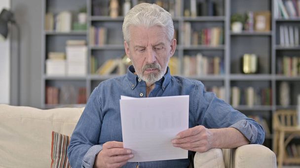 Alter Mann liest zu Hause Dokumente - Foto, Bild