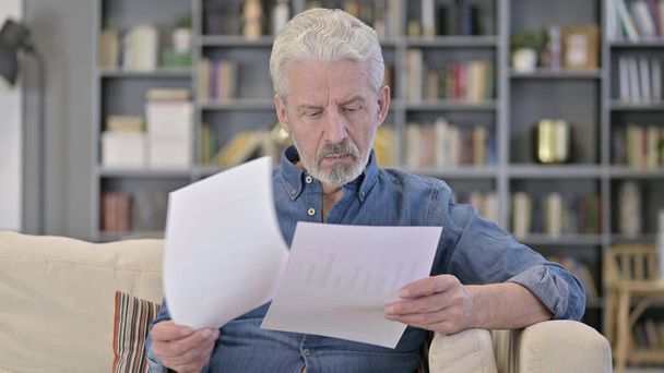 Alter Mann liest Dokumente auf Sofa - Foto, Bild
