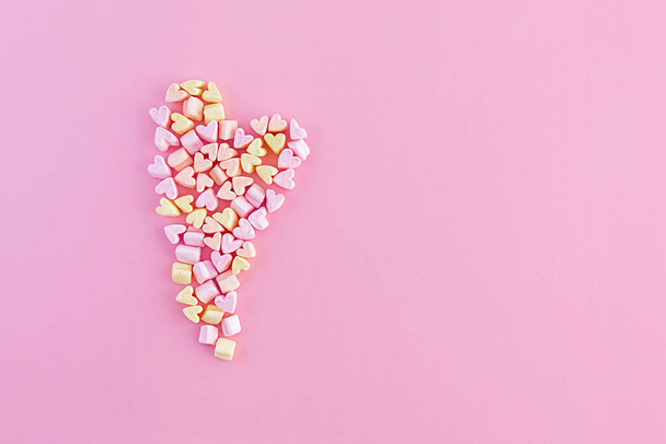 Big heart made of small multi-colored marshmallows on a pink background. Copy space. - Photo, image