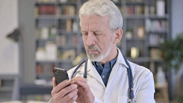 Retrato de Profesional Senior Old Doctor usando Smartphone
 - Foto, Imagen