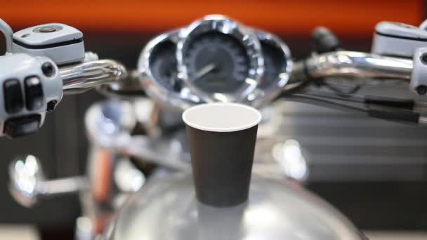 Hombre agita el café con una llave inglesa en un tanque de gasolina de una motocicleta
. - Imágenes, Vídeo