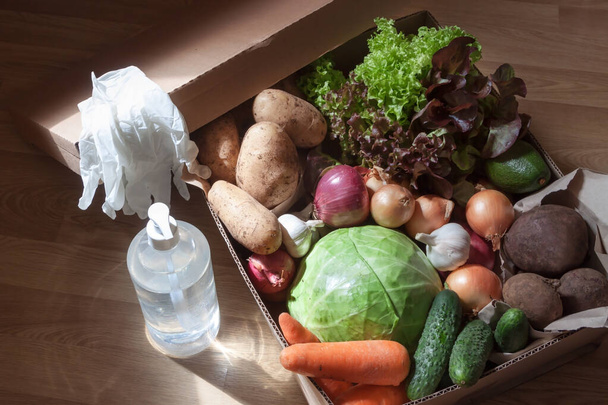 Close up from above online home food organic potatoes, onions, cabbage, beets, lettuce, garlic, carrots, avocado delivery with disinfectants hand disanitizer, disposable gloves on the floor background. Пандемический ковид-2019 и далее к безопасной жизни
  - Фото, изображение