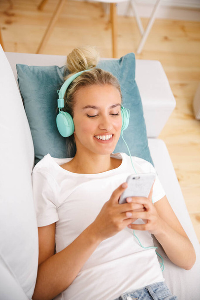 Young woman with smartphone and headphones at home. - Foto, imagen