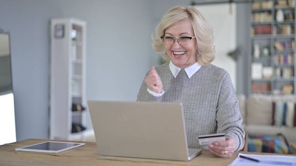 Vieja mujer teniendo éxito pago en línea en el ordenador portátil
 - Foto, imagen