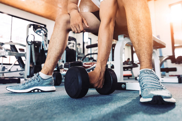 A man pick dumbbell on the floor at fitness gym with sun light. - 写真・画像