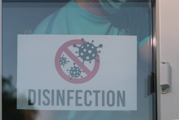 DISINFECTION tábla egy ajtó bolt vagy helyreállító. A bolti alkalmazott fertőtlenítési bejelentést tesz. Fertőtlenítés törés a koronavírus világjárvány idején. A koronavírus-fertőtlenítést zárt térben végzik.. - Fotó, kép
