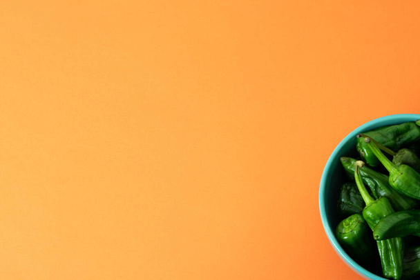 Plato con pimientos Padrón sobre fondo naranja. Copiar espacio
 - Foto, imagen