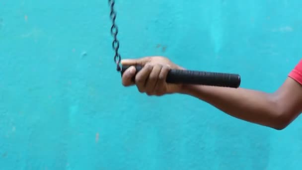 Обучение нунчаку. Молодой мальчик практикует нунчаку на открытом воздухе изолированы на голубом фоне
. - Кадры, видео