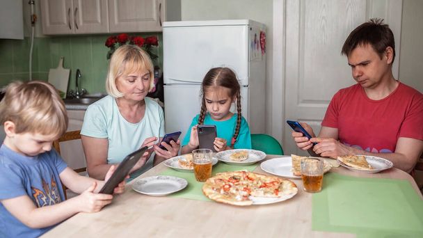 Большая семья из нескольких поколений ужинает вместе, но каждый пишет смс на свой смартфон, цифровое отравление, новая нормальность
 - Фото, изображение