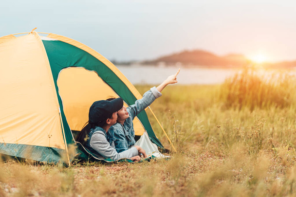 Two young friends are lying in a tent in nature, one woman is pointing to the sky. - Fotoğraf, Görsel