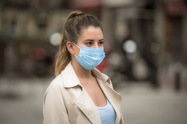 Coronavirus karantinası sırasında tıbbi maskeli bir kız sokakta yürüyor. - Fotoğraf, Görsel