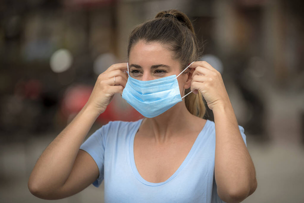 女の子はコロナウイルスの隔離中通りに医療マスクをつけて - 写真・画像