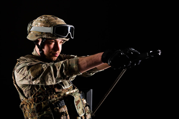 Soldat mit Gewehr zielt auf die Zielscheibe auf schwarzem Hintergrund. Konzept des Krieges. - Foto, Bild