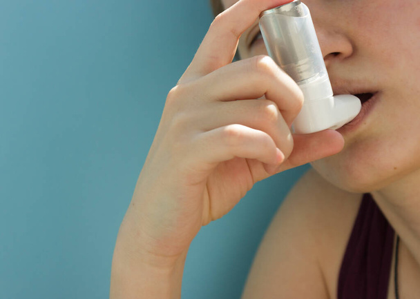 Dia Mundial da Asma Maio 5.inalador anti-asma em um fundo azul.teenager usa um inalador
. - Foto, Imagem