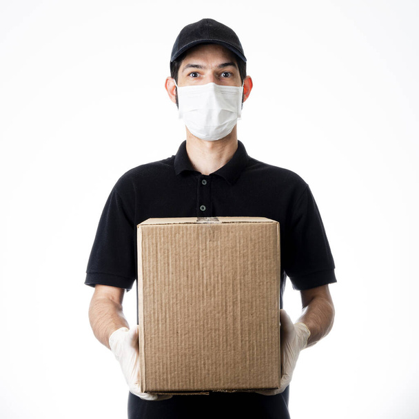 Delivery man holding cardboard box with gloves and mask. Grey background. Delivery shipping. Online shopping and express delivery during quarantine. - Foto, Imagem
