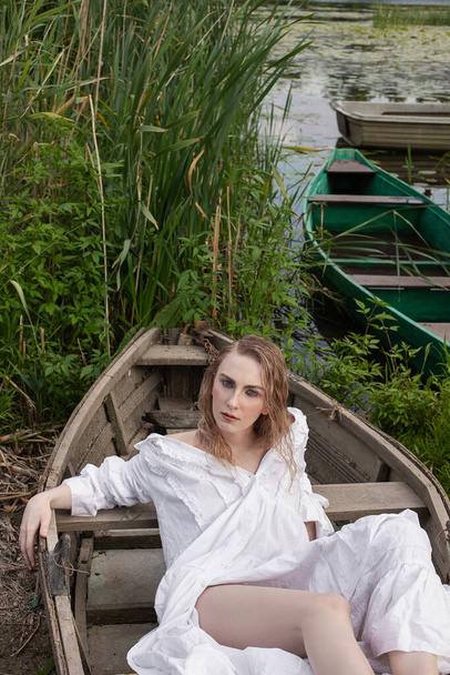 Girl in a white dress sitting in a boat - 写真・画像