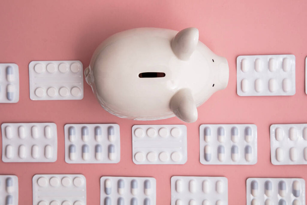 Healthcare cost. Money box piggy bank with packets of pills and tablet - Foto, Imagen