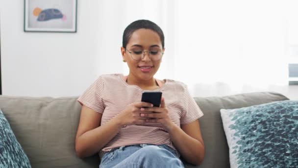 mujer afroamericana con smartphone en casa - Metraje, vídeo