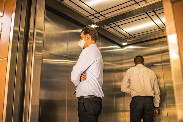 Distanciation sociale sur ascenseur avec 4 passagers se tiennent dans le coin de l'épidémie de coronavirus covid19 situation. Concept de prise de conscience sûre et à faible risque
. - Photo, image